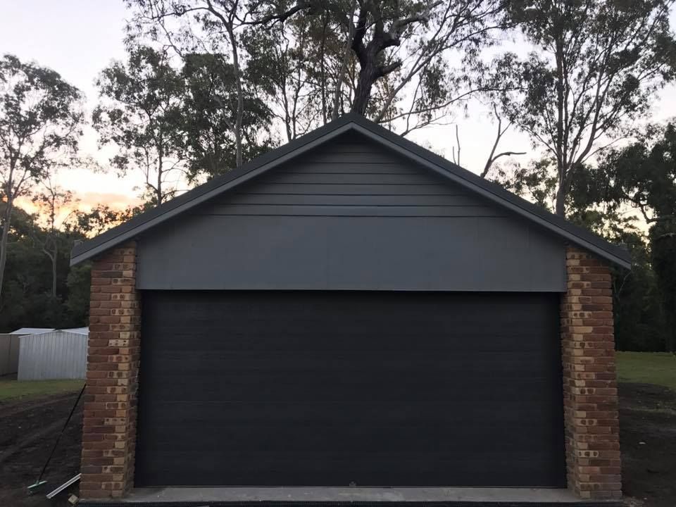 A garage with a brick wall and a black garage door.