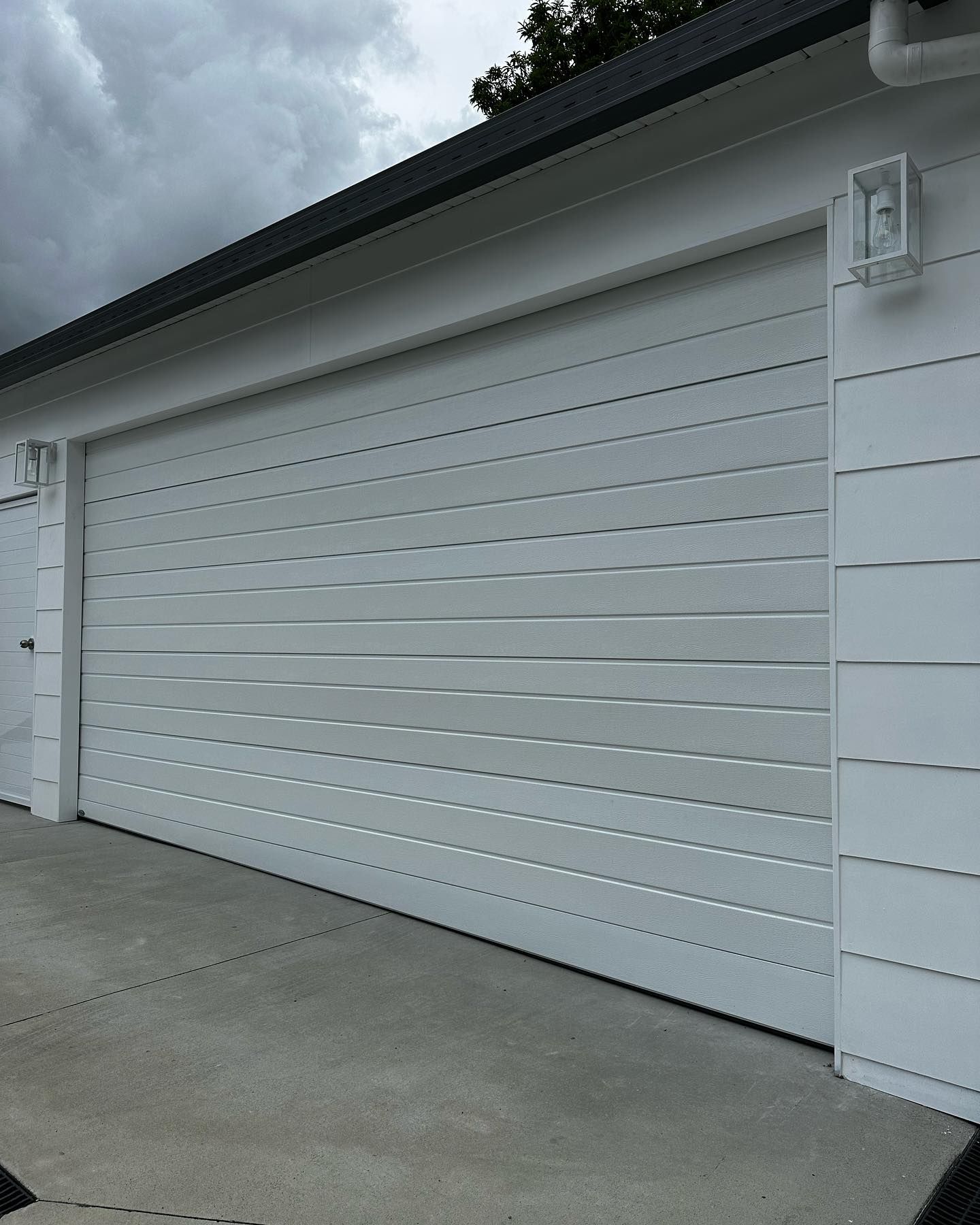 A white garage door is open on a cloudy day.