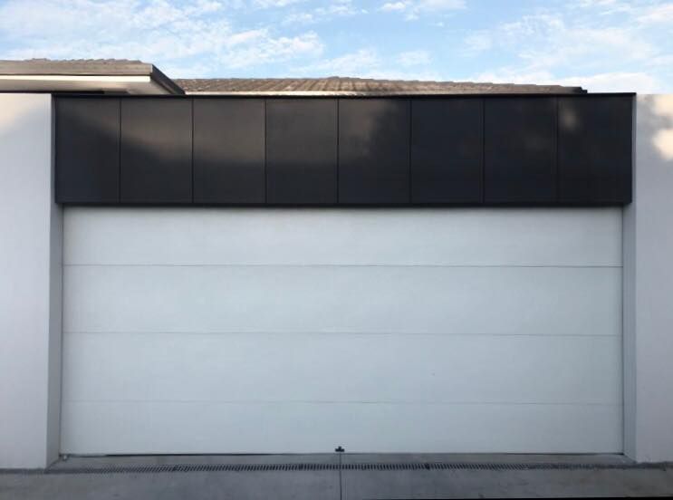 A white garage door with a black trim on the side of a building.
