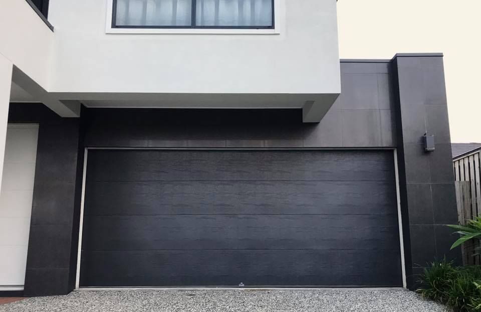 A black garage door is open in front of a white house.