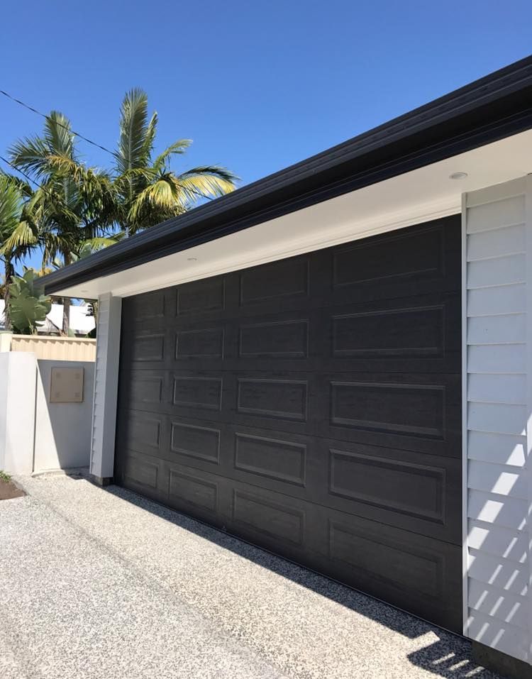 A black garage door is sitting on the side of a house.