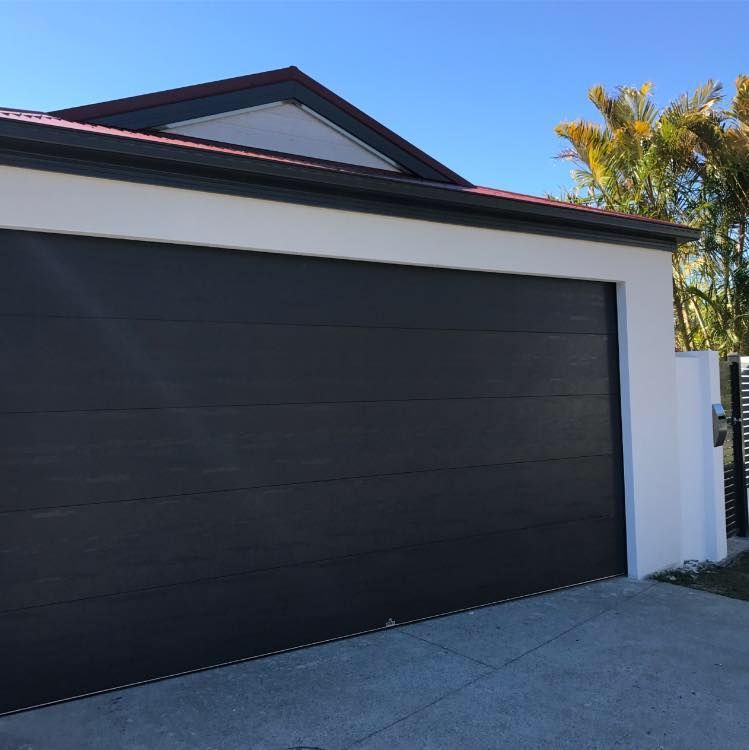 A black garage door is open in front of a white house