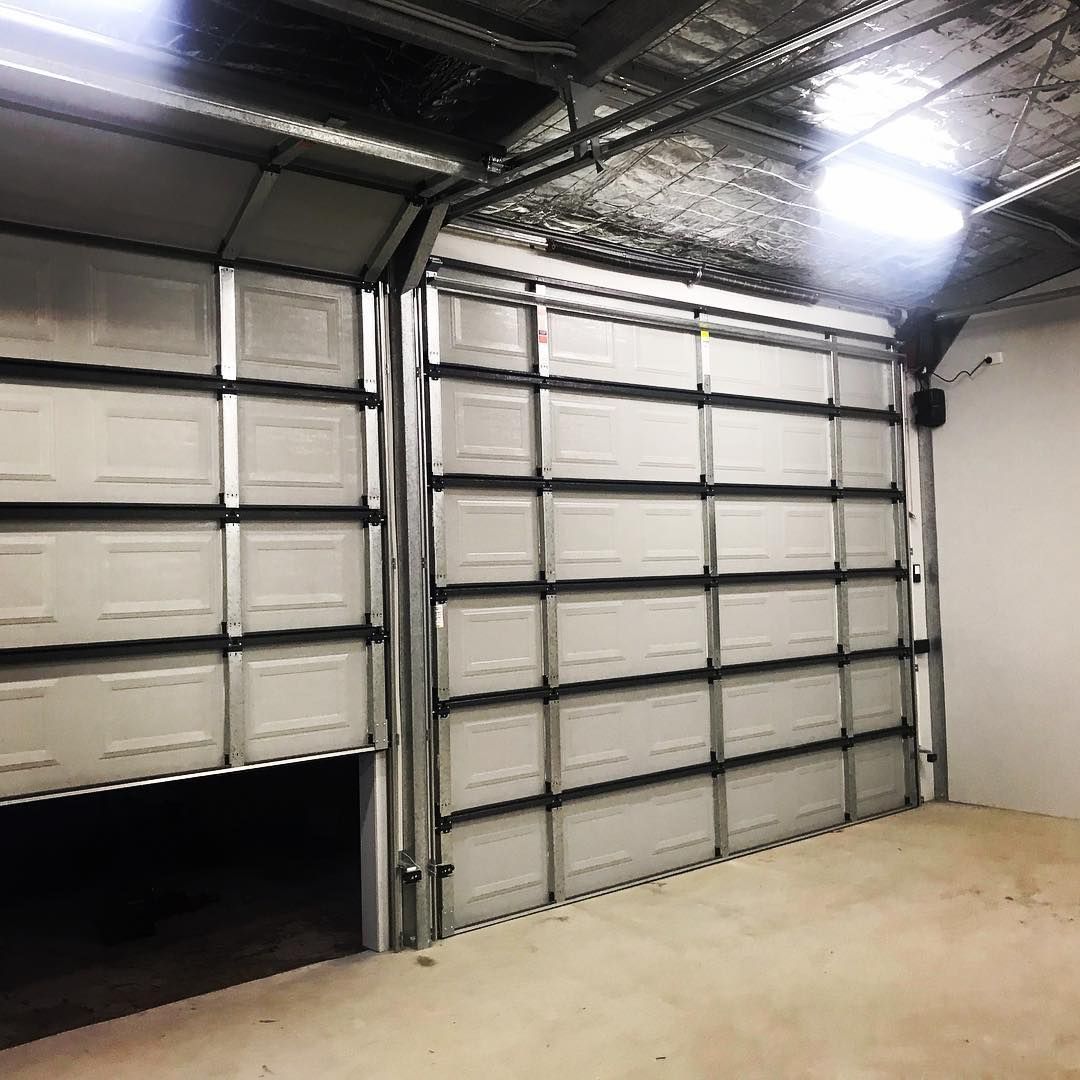 A garage with two garage doors open and a light on the ceiling.
