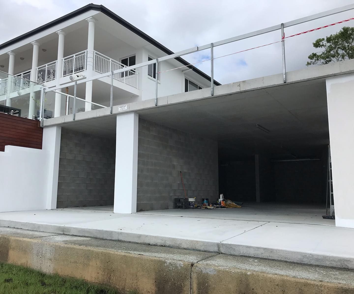 A large white house with a balcony and a garage underneath it.
