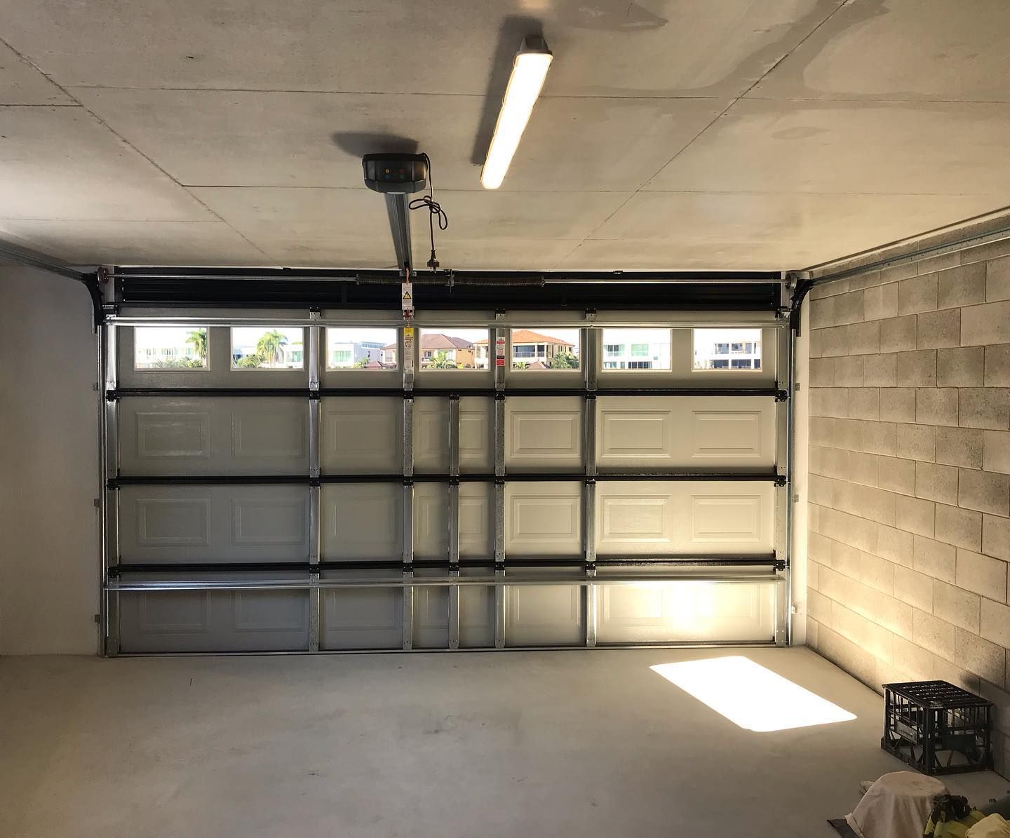 An empty garage with a garage door open and a light on the ceiling.