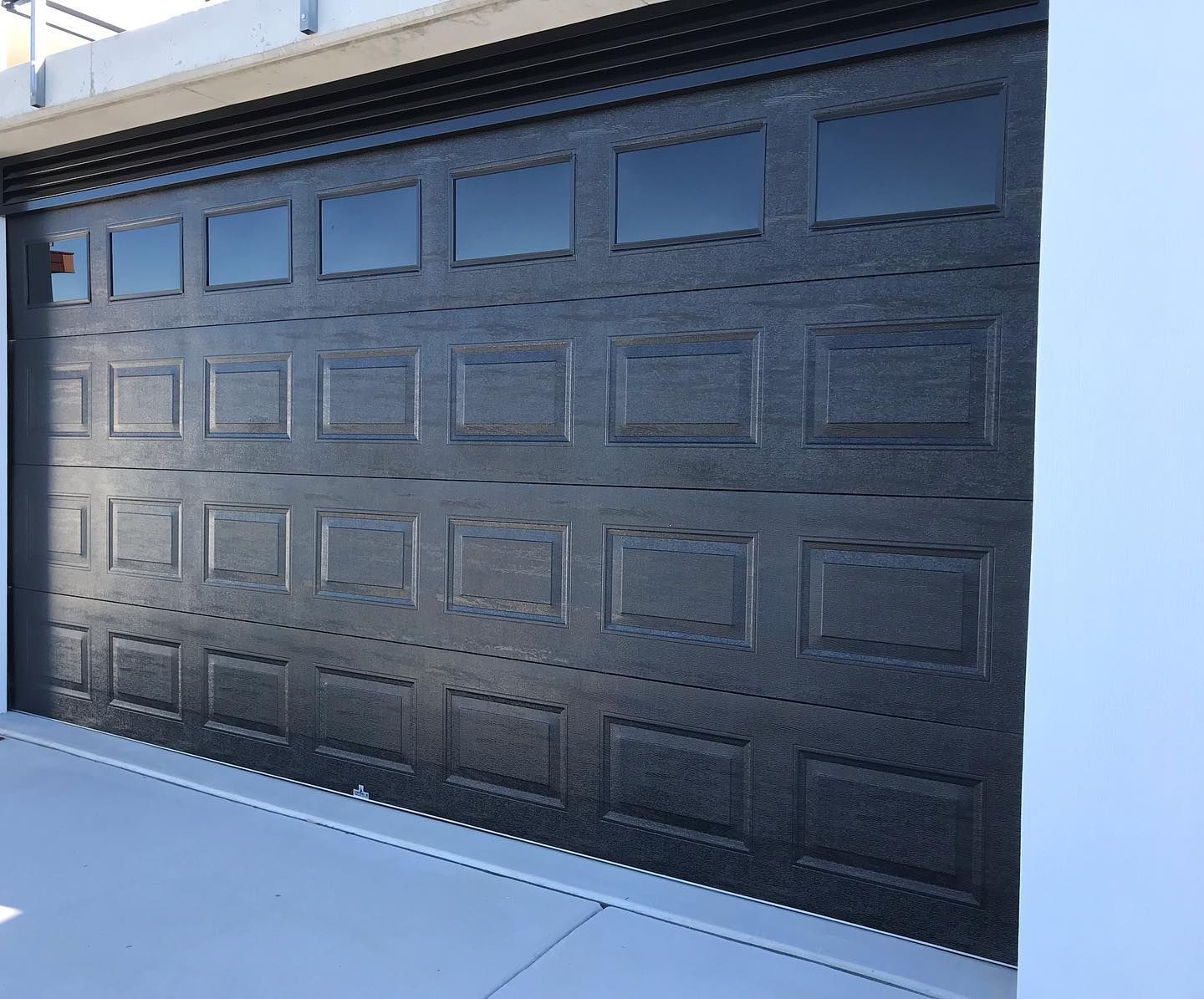 A black garage door with a lot of squares on it