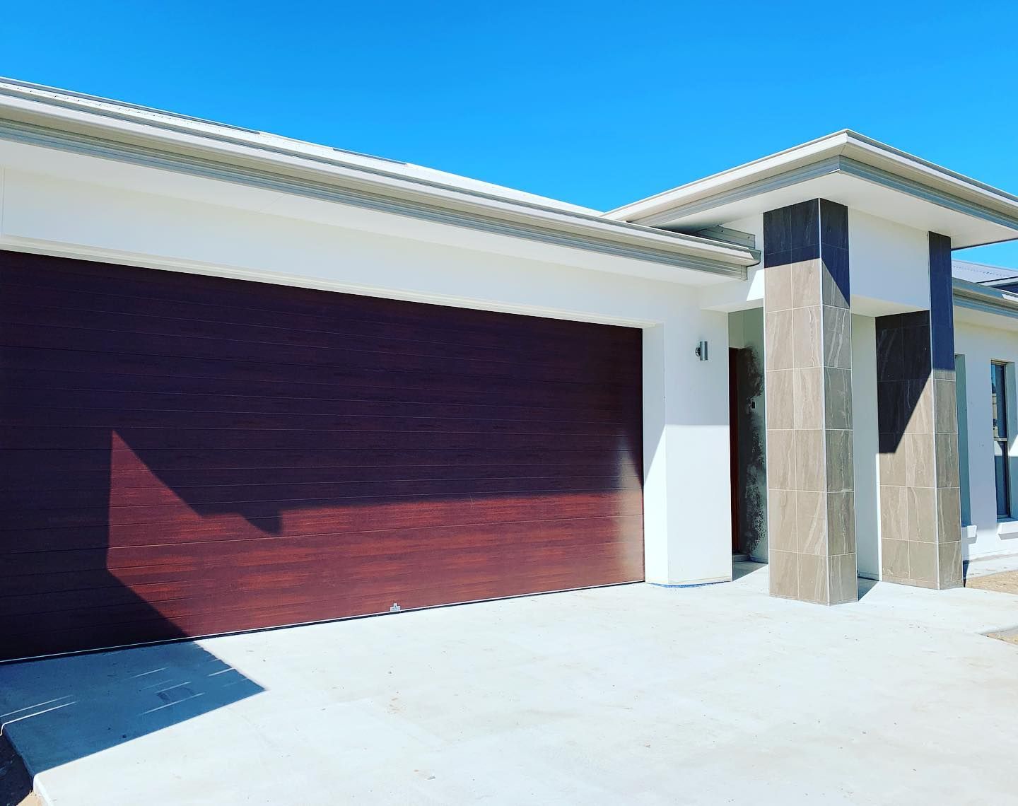 A white house with a red garage door and columns.