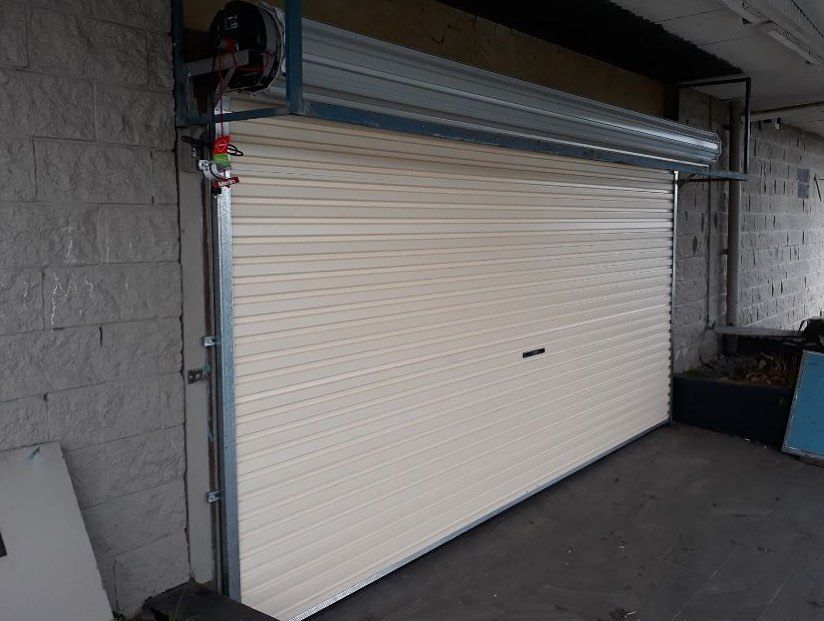 A white garage door is sitting in a garage next to a brick wall.