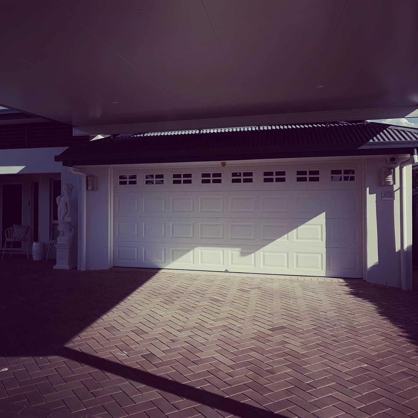 A white garage door on a brick driveway