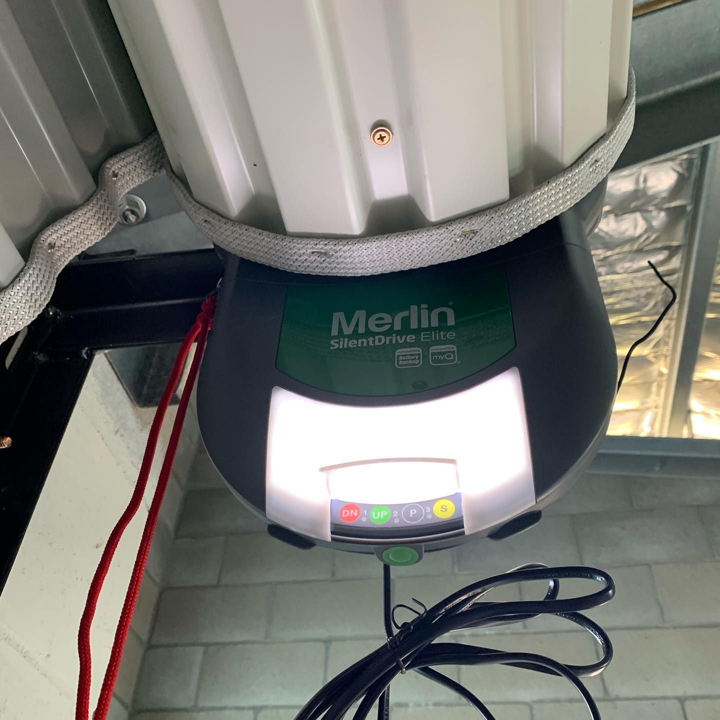 A merlin brand garage door opener is hanging from the ceiling