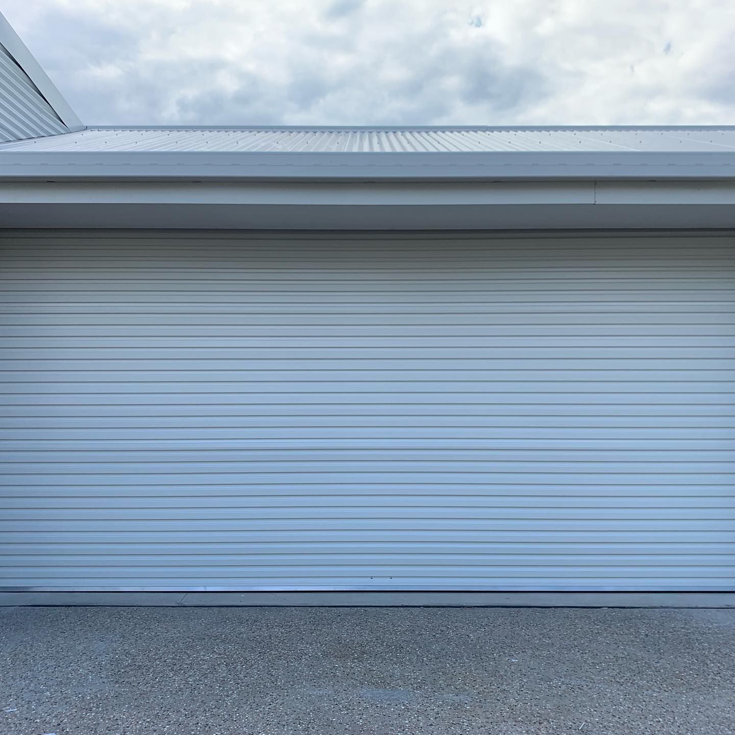 A white garage door with a cloudy sky in the background.