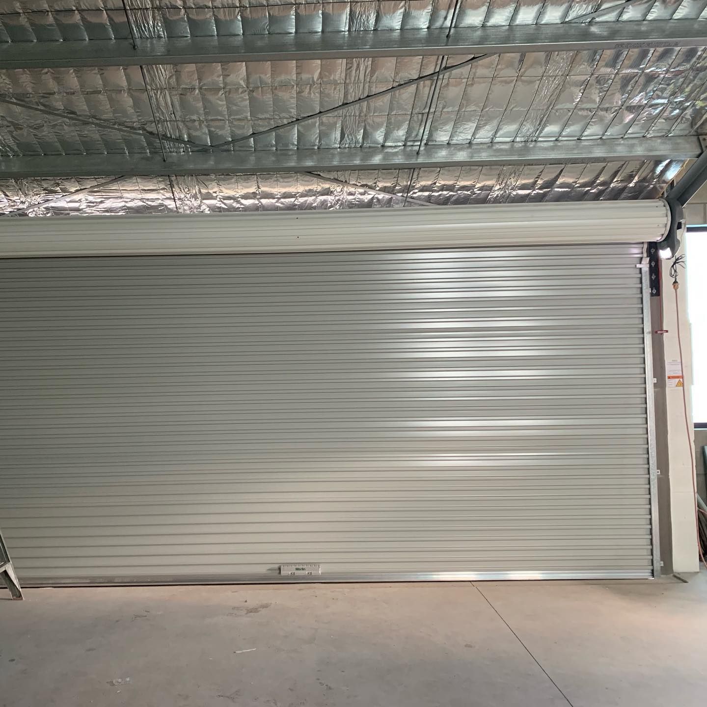 A white garage door is open in a building.