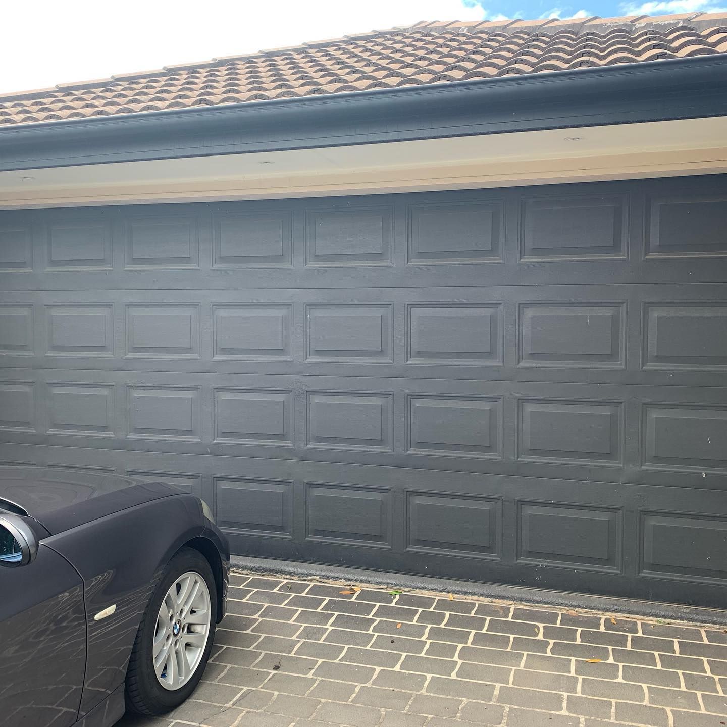 A car is parked in front of a garage door.