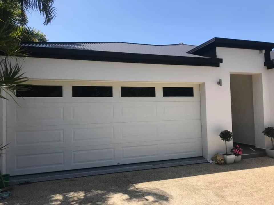A white house with a black roof and a white garage door.