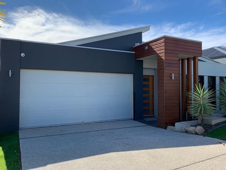 A modern house with a white garage door and a driveway.
