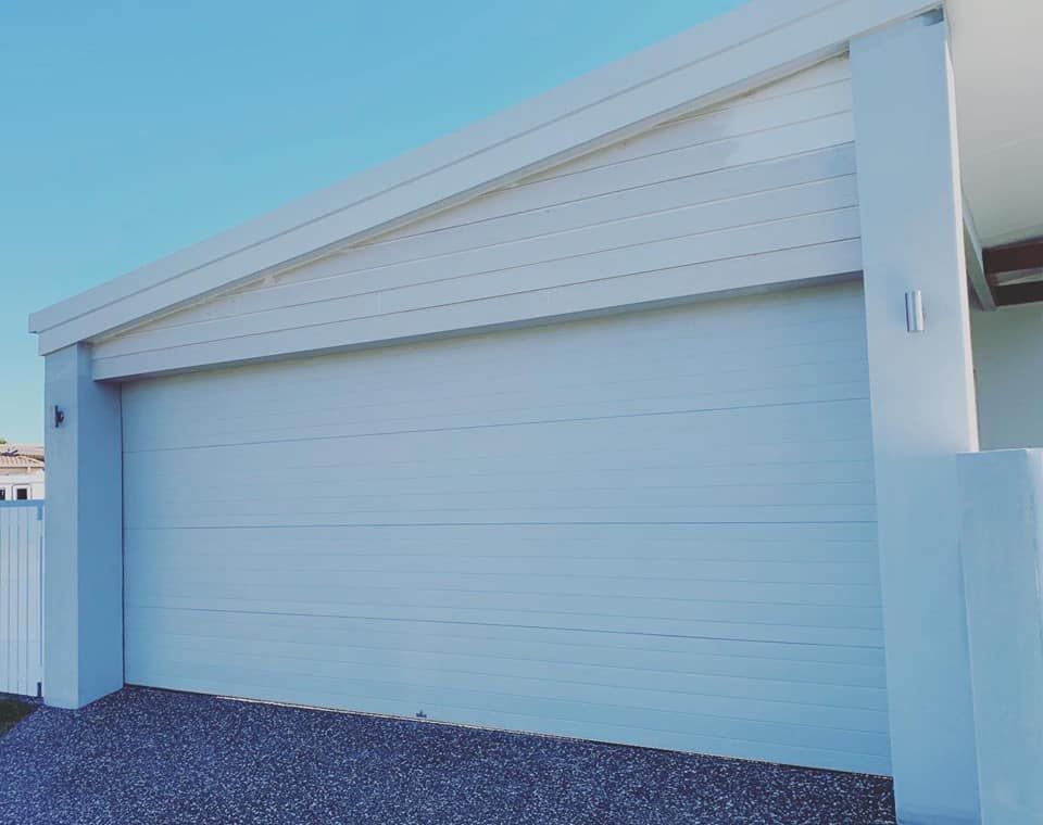 A white garage door is open in front of a house.