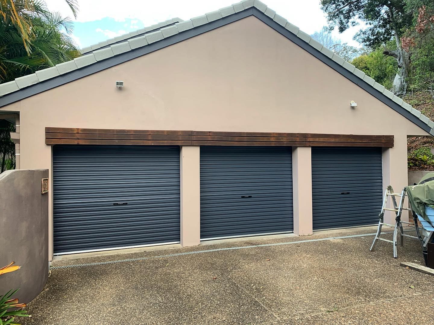 A large house with two garage doors and a ladder in front of it.