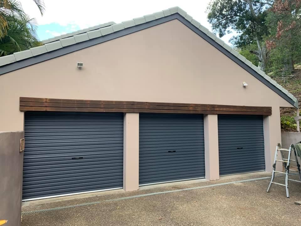 A garage with three garage doors and a ladder in front of it