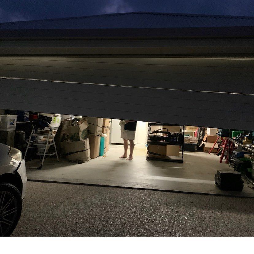 A woman is standing in a garage behind a garage door.