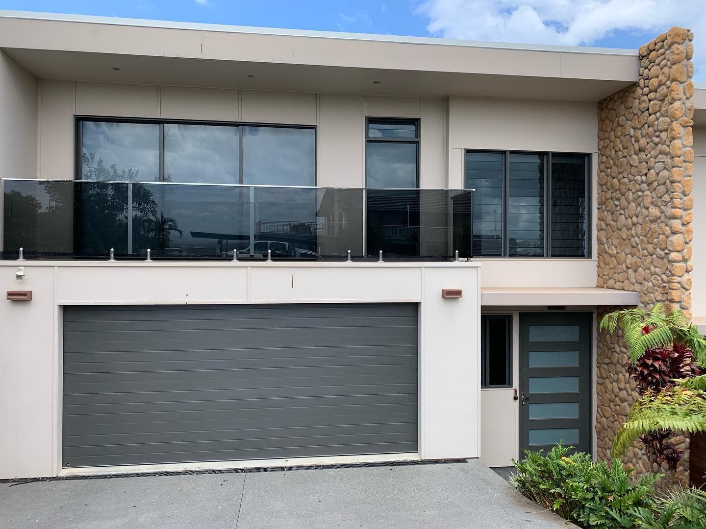 A modern house with a gray garage door and a balcony