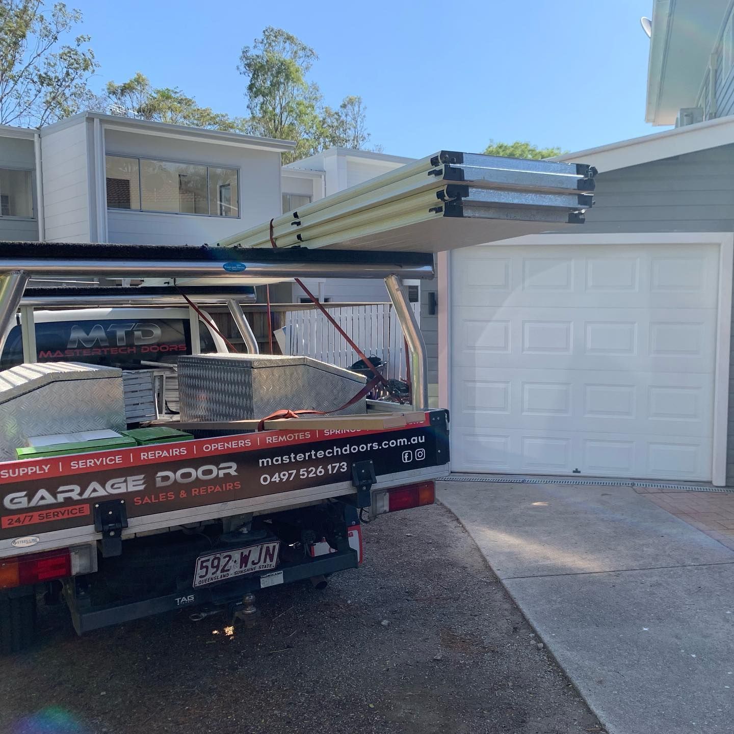 A garage door company truck is parked in front of a garage door.