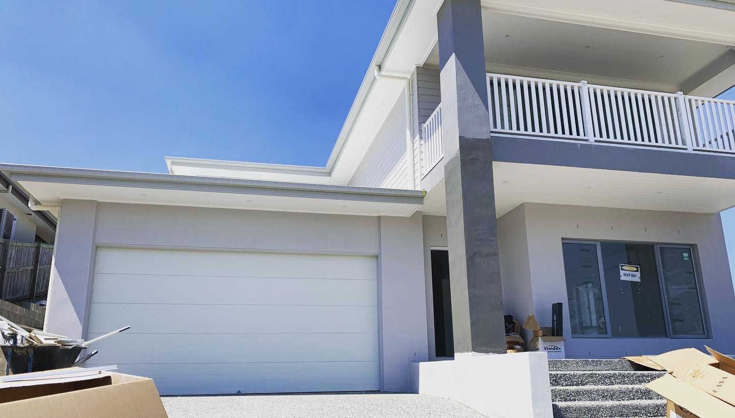 A large white house with a white garage door and a balcony.