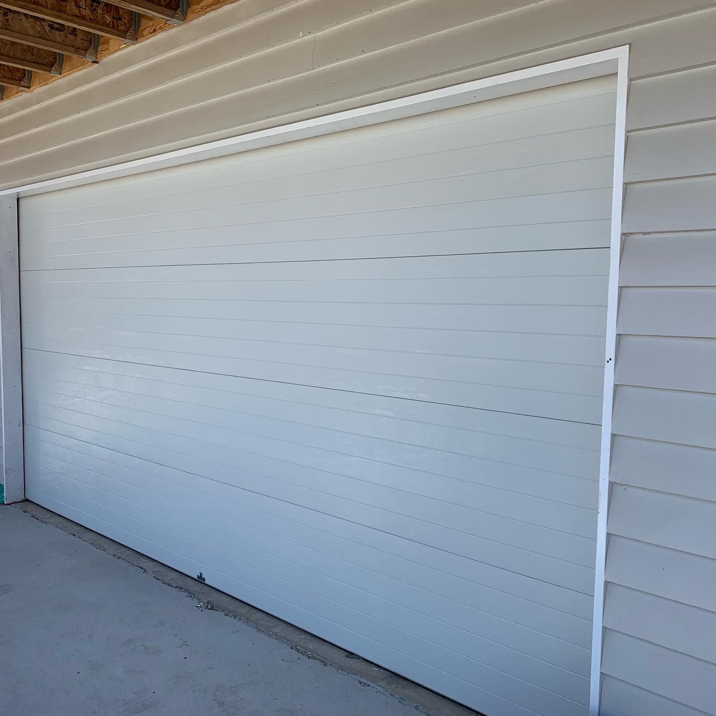 A white garage door is sitting on the side of a building.