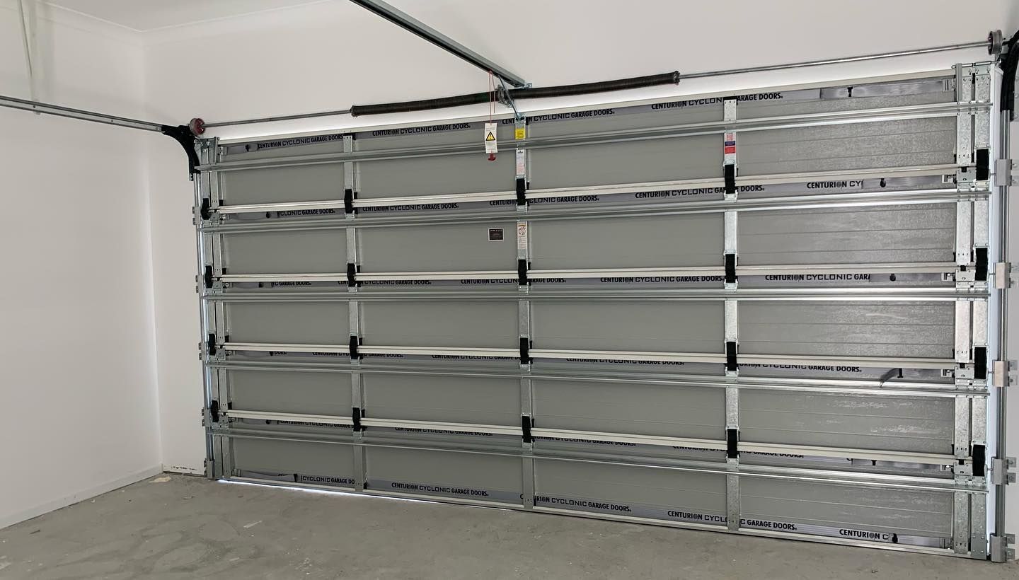 A garage door is open in an empty garage.