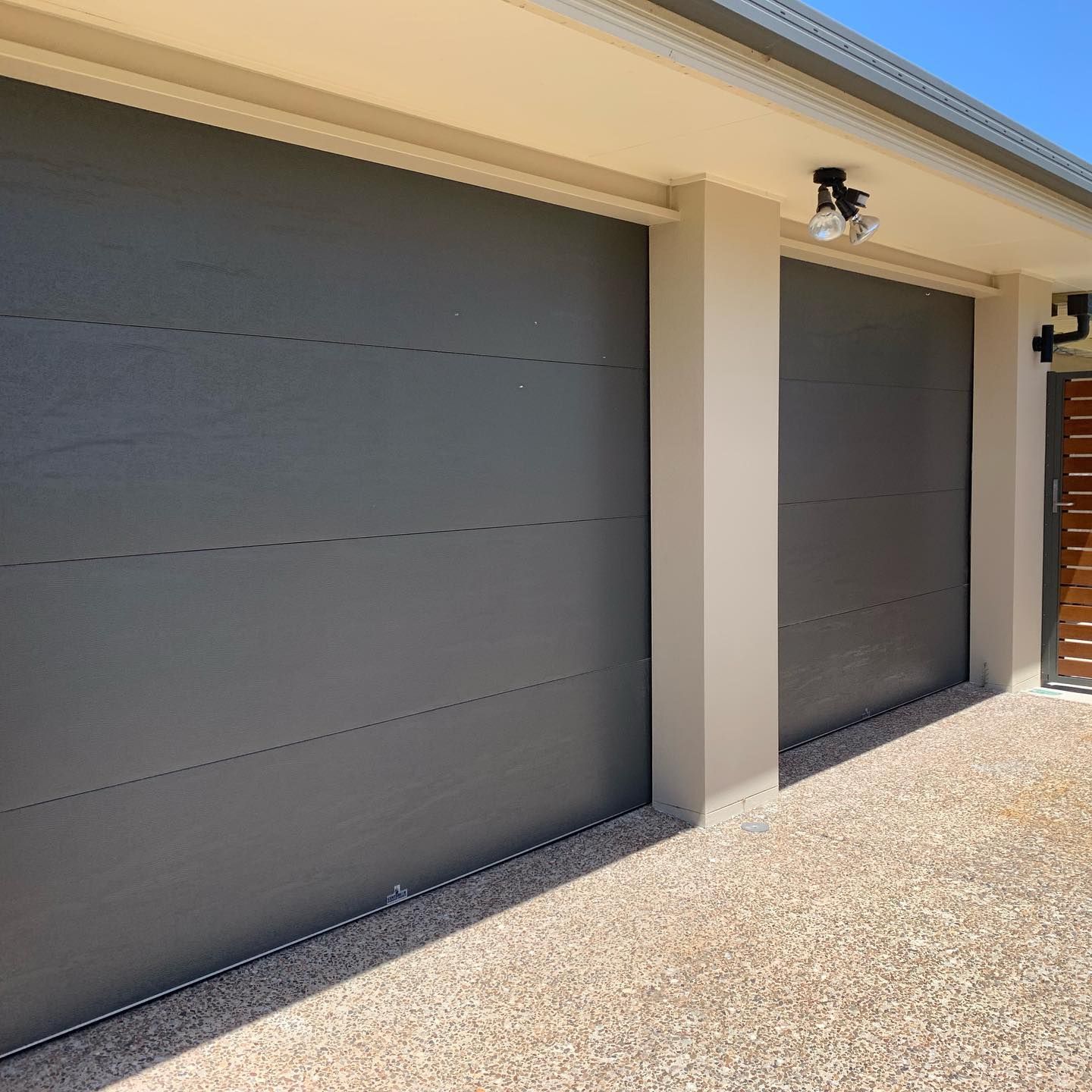 A couple of garage doors sitting next to each other on the side of a house.