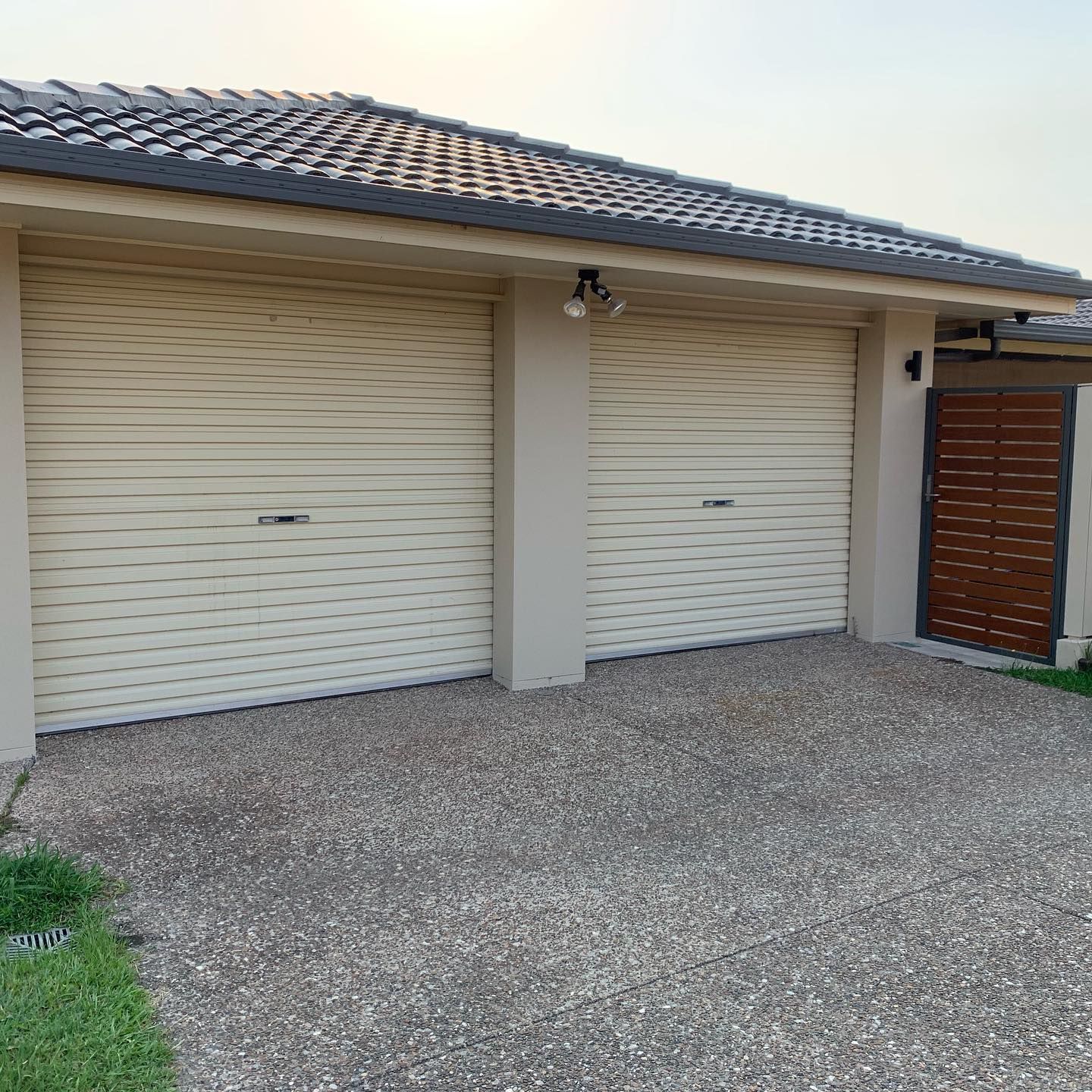 A garage with two white garage doors and a wooden gate.