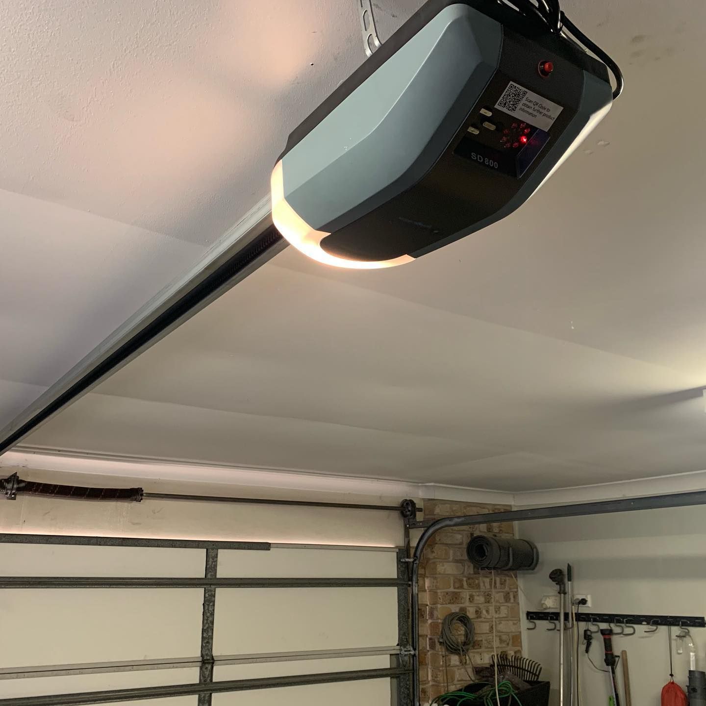 A garage door opener is hanging from the ceiling in a garage.
