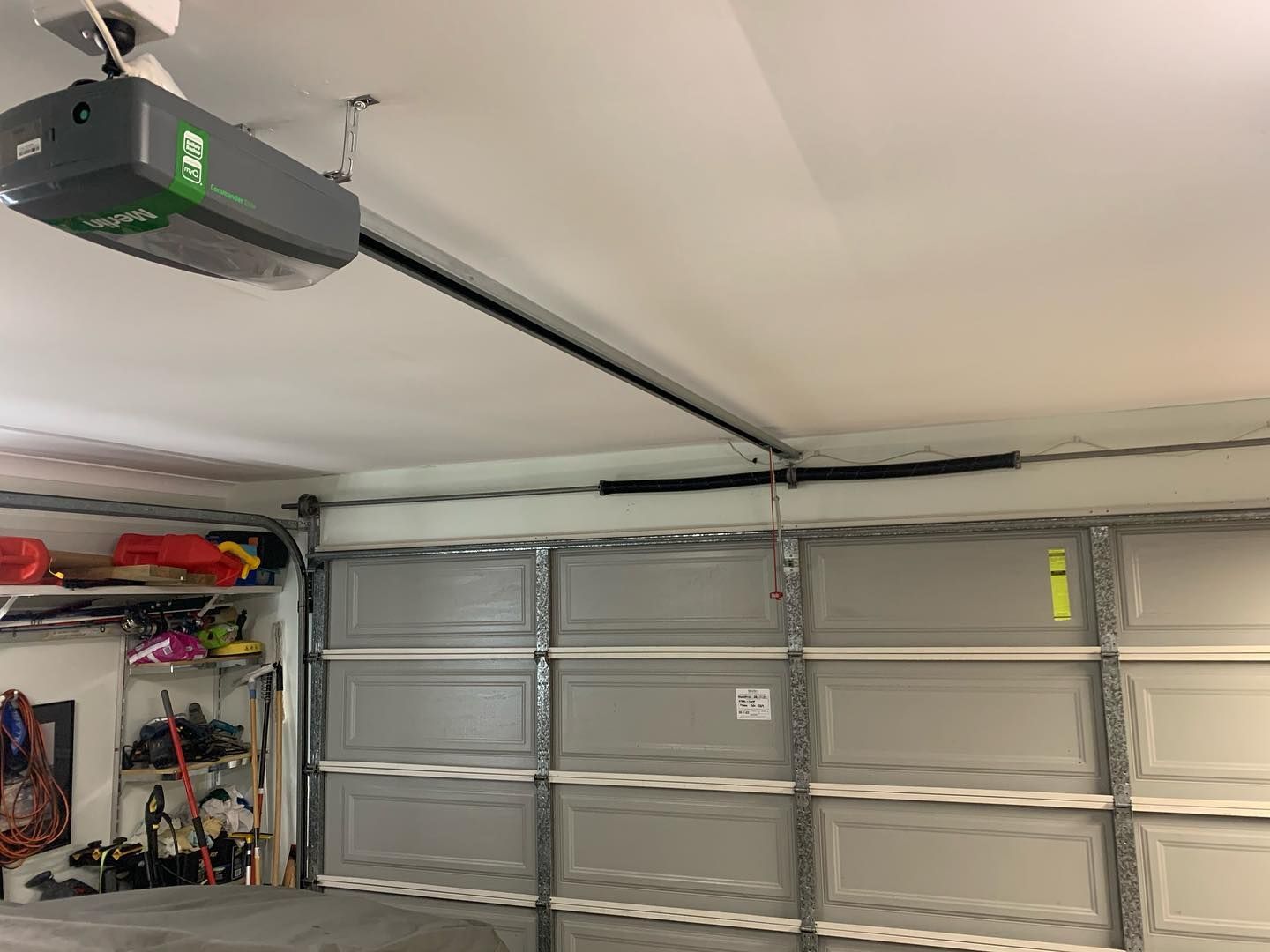A garage door opener is hanging from the ceiling in a garage.