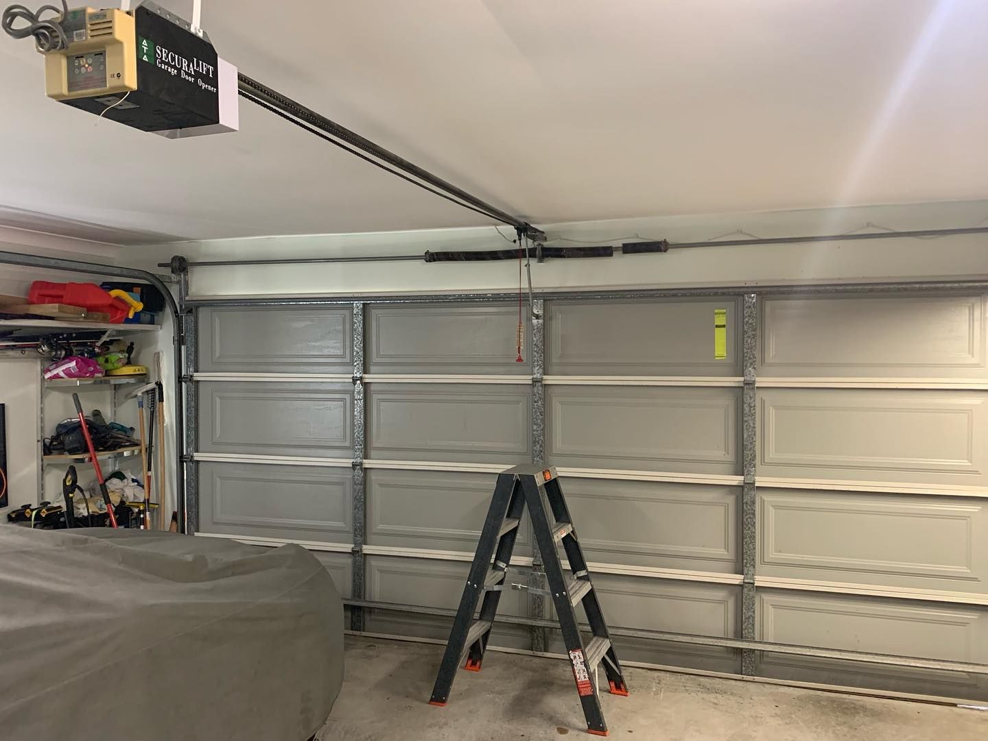 A garage with a garage door opener and a ladder.