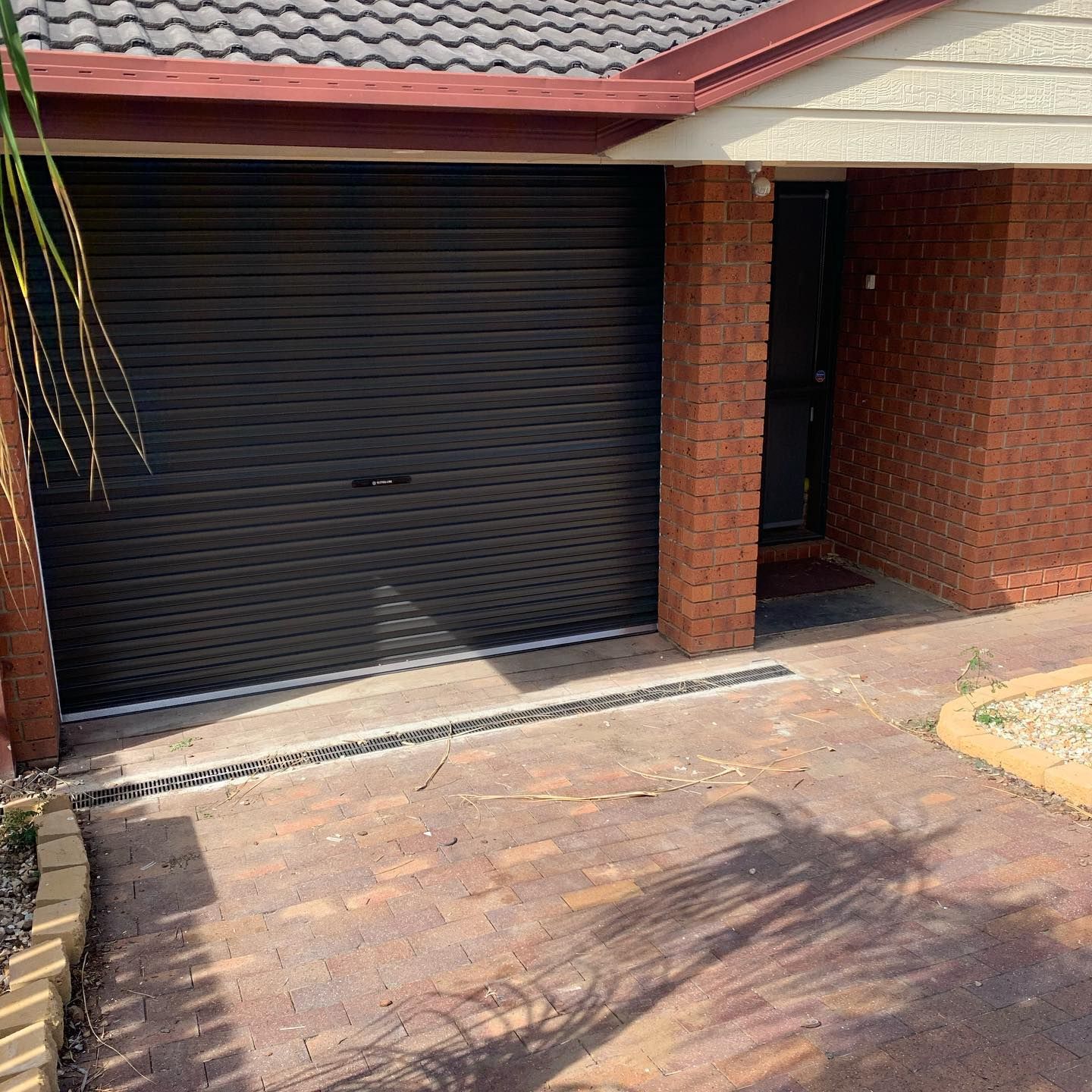 A black garage door is sitting in front of a brick house.