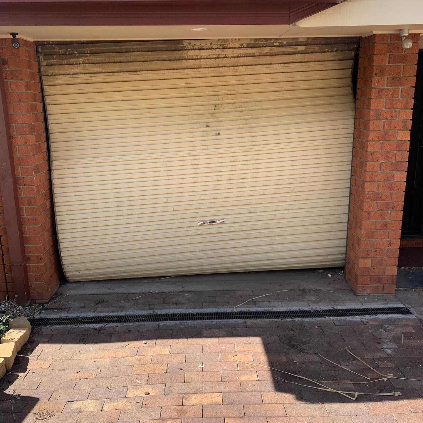 A garage door with a brick wall behind it is open.