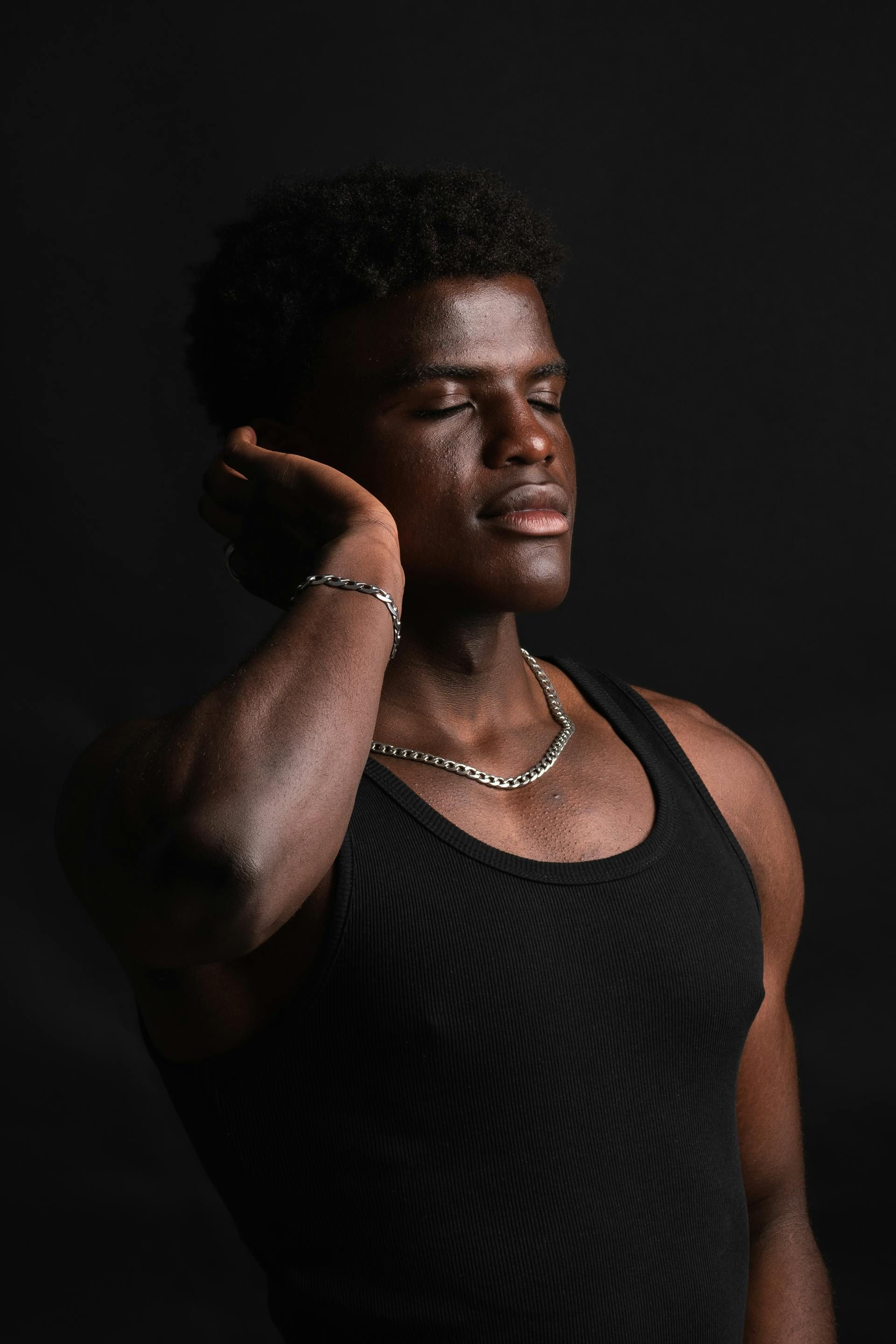 The man is wearing a black tank top and a necklace.