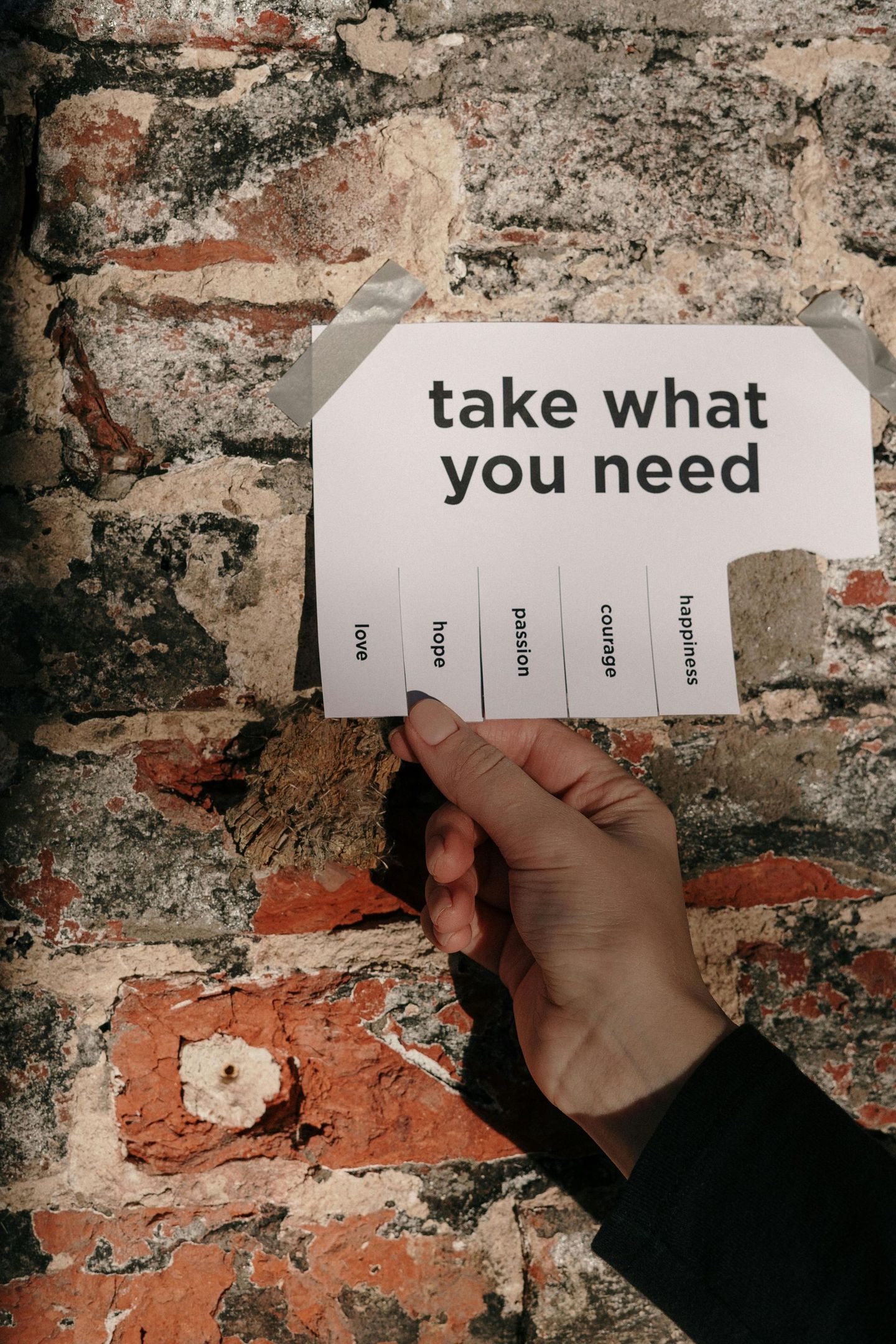 A person is holding a piece of paper that says take what you need.