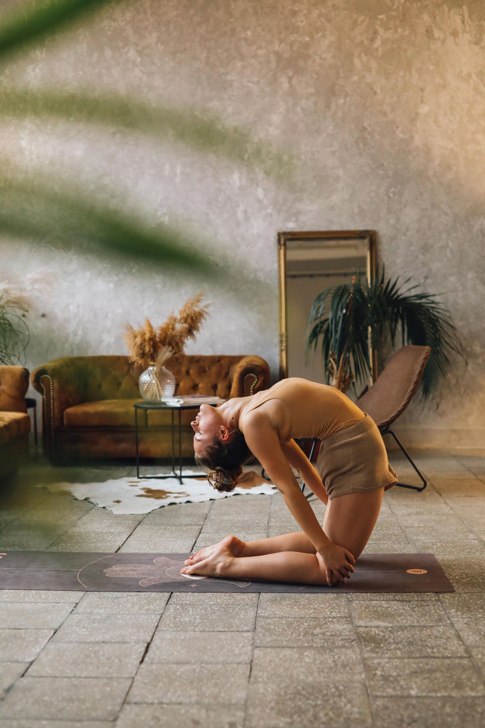A woman is doing a yoga pose on a yoga mat in a living room.