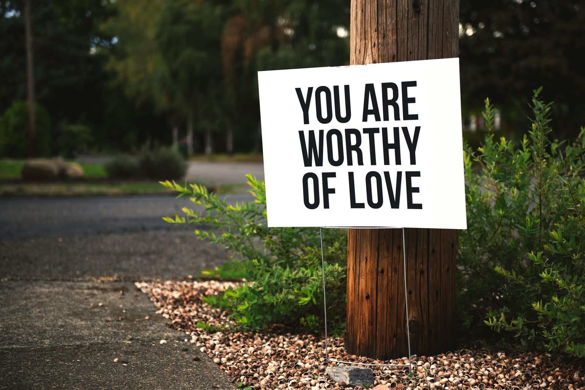 A sign on a wooden pole that says `` you are worthy of love ''.