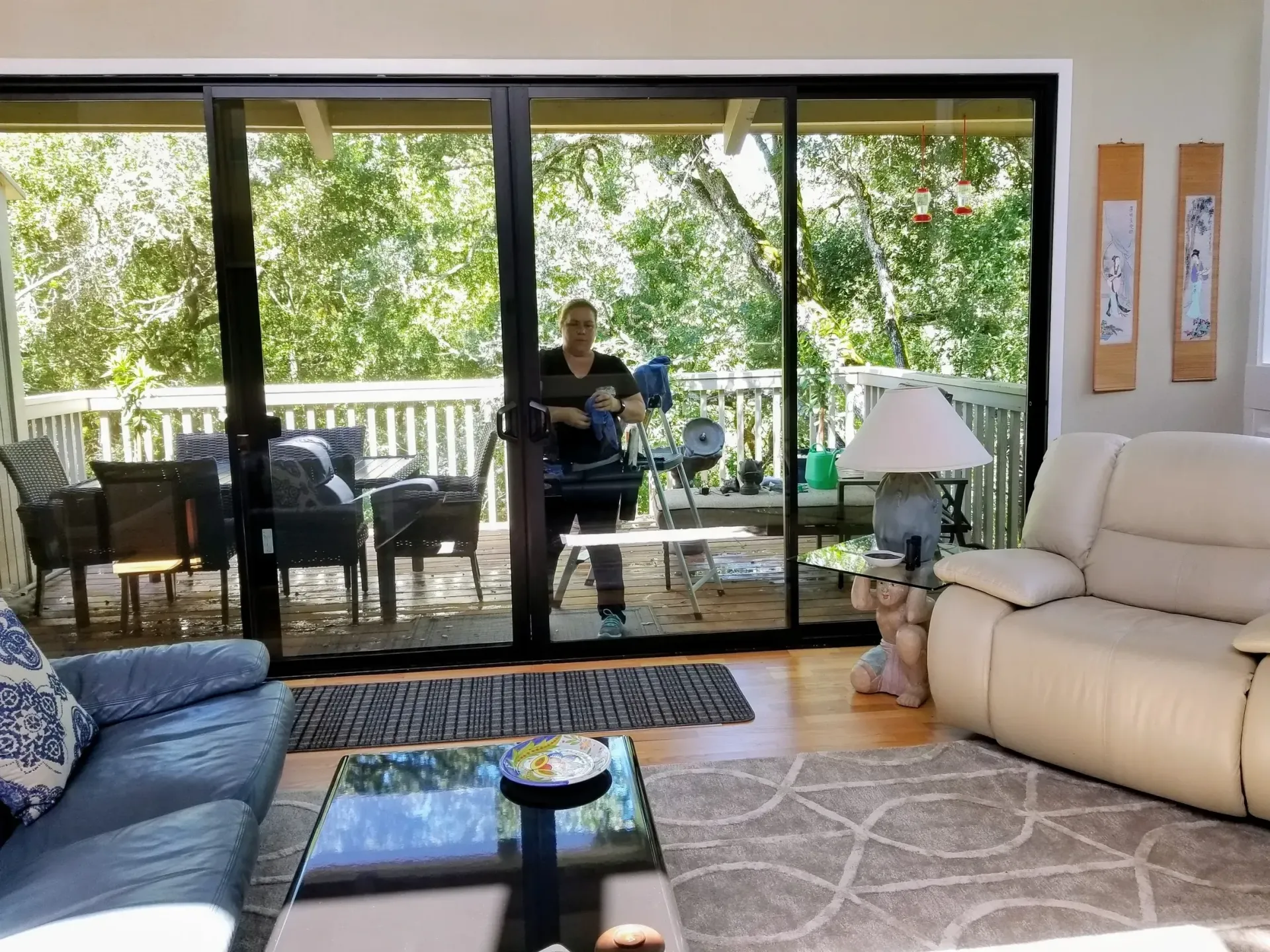 Living room with sliding glass door, person on deck, beige recliner, blue couch, table.