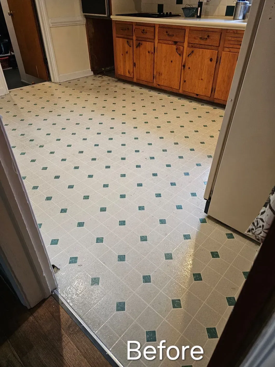 A kitchen floor with a blue and white square pattern, with cabinets visible.