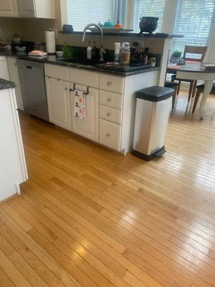 Kitchen with hardwood floors, white cabinets, and a black countertop island with a sink.