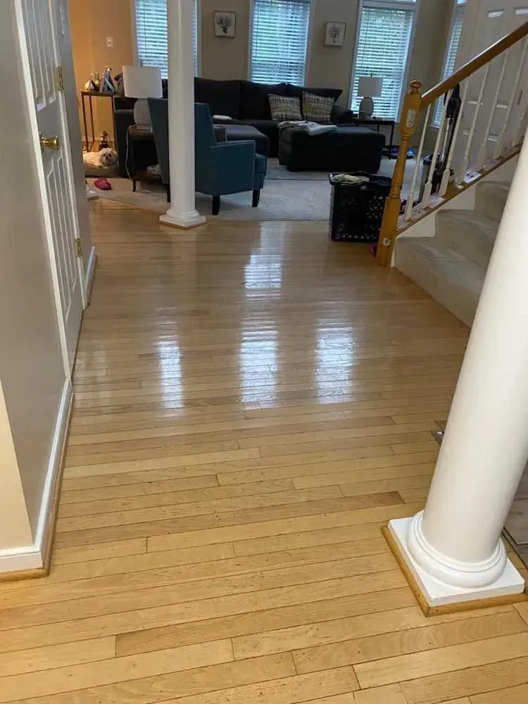 Hardwood floor in a home with white pillars, stairs, and furniture in the background.