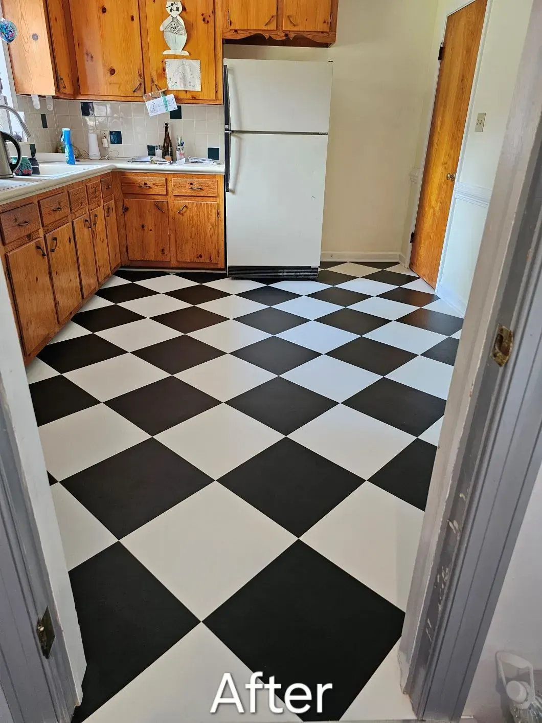 Black and white checkered kitchen floor with wooden cabinets and a refrigerator.