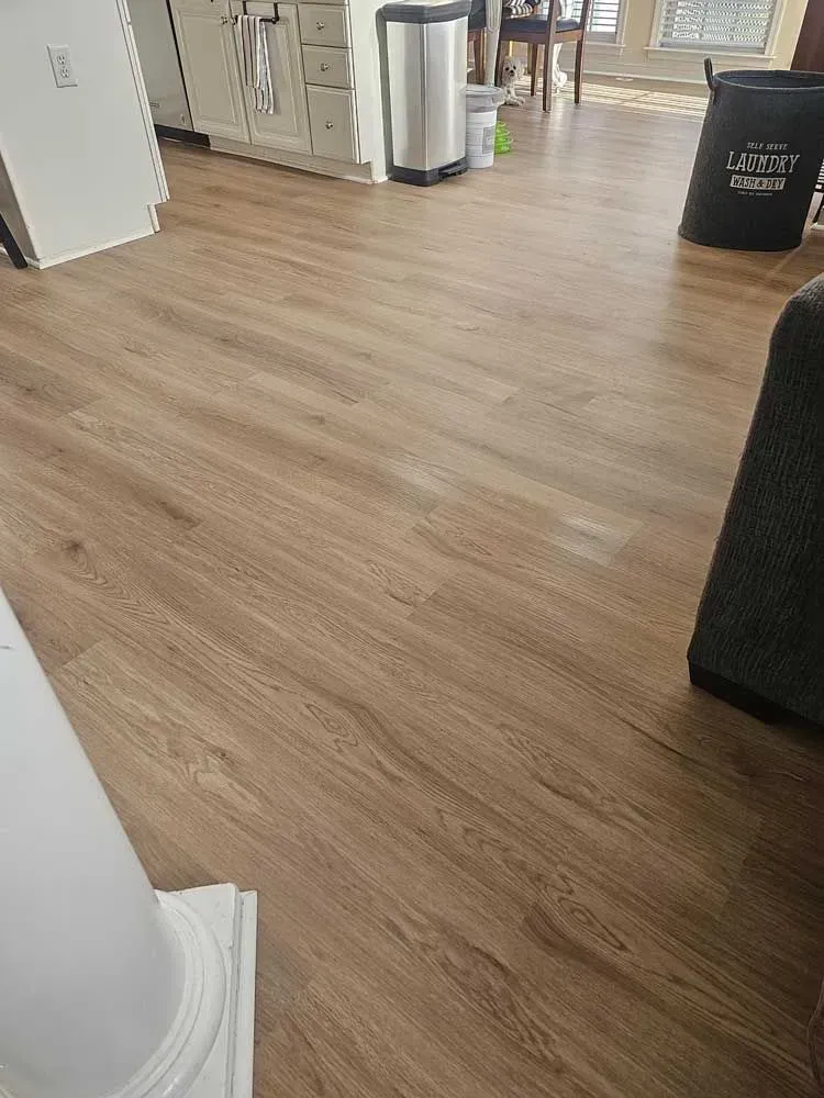 Light brown wood-look flooring in a room with a white column, cabinet and trash can.