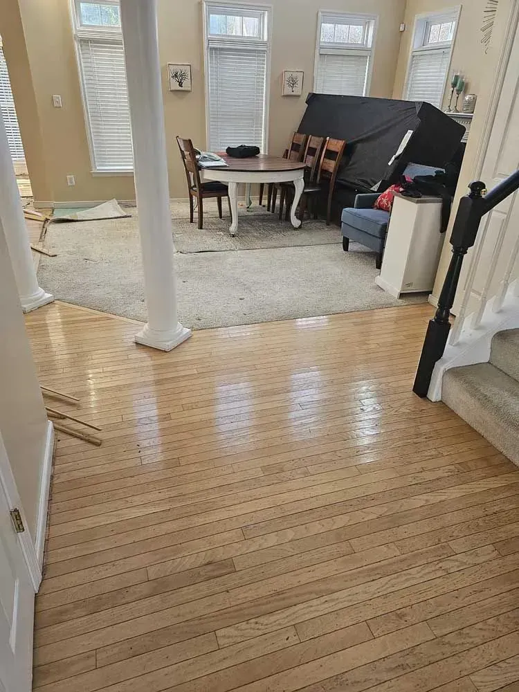 Hardwood floor leads to a living area with a rug, table, chairs, sofa, and a staircase.