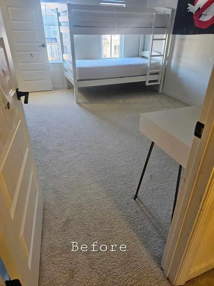 Bedroom with white bunk beds, desk, and carpeted floor. Doorways visible.