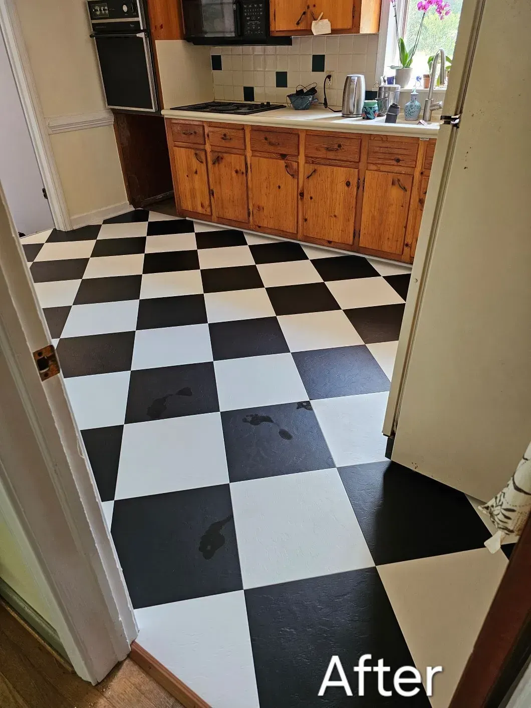 Black and white checkered floor in a kitchen with wooden cabinets.