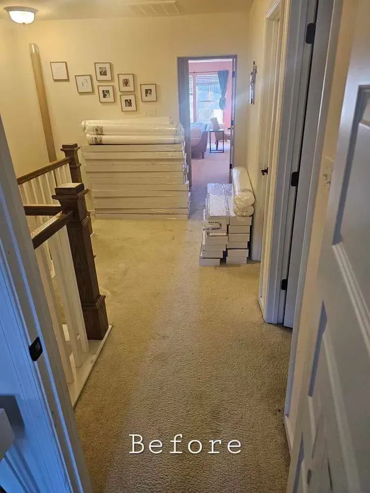 Hallway with carpet and stairs. Boxes stacked on floor. Doors on both sides. 
