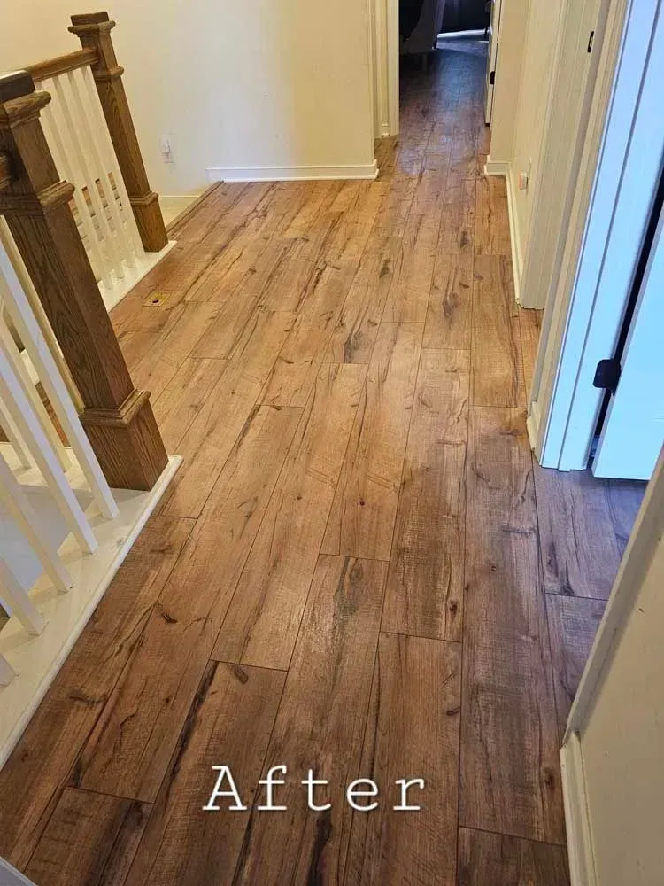 Wooden-look flooring in a hallway with white doors, walls and a staircase. 